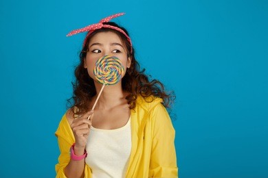 attractive young asian woman eating sweet lollipop