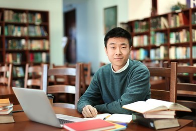 asian student with laptop studying in library