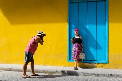 man taking a photo of a girl in havana cuba against a yellow wall