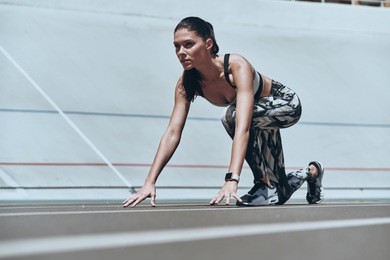 ready to run. beautiful young woman in sports clothing standing on the start line while running outdoors        