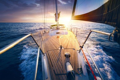 sunset at the sailboat deck while cruising / sailing at opened sea. yacht with full sails up at the end of windy day. sailing theme - background.