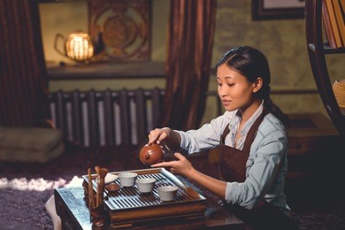 young tea master pouring tea in room
