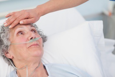 nurse touching the forehead of a patient in hospital ward