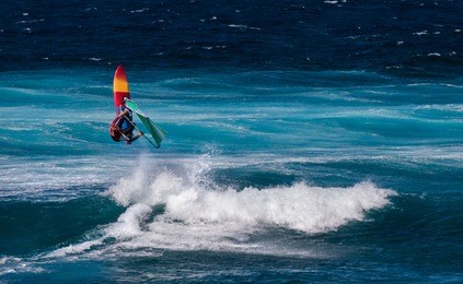 professional windsurfer riding waves at sunny windy day in the atlantic ocean. windsurfing, extreme sport. canary isalnds, tenerife, la caleta