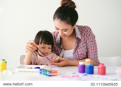 a happy family is painting. mom help her daughter drawing