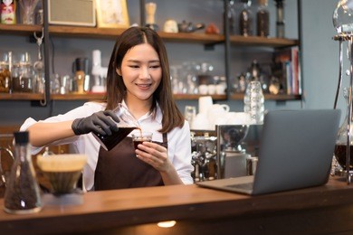 beautiful young asian caucasian bartender barista or manager using laptop and coffee brewing method whole process at modern coffee shop.start up small business owner food and drink concept.