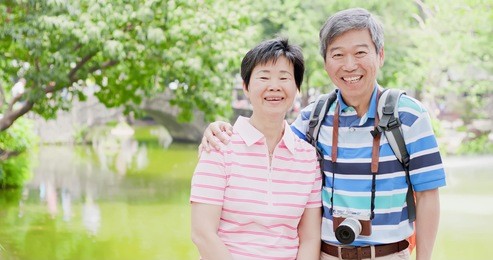old couple smile happily and go travel in the park