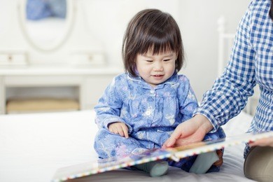 baby girl reading book with mom at home