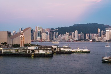 the star ferry pier in tsim sha tsui in kowloon with the skyline of hong kong island in the background across the victoria harbor in hong kong, china