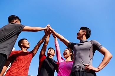 team of asian young adult sportsmen and sportswoman putting hands together to show unity and teamwork spirit.