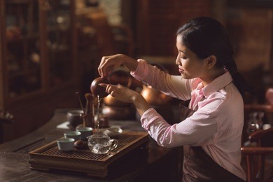 young master pouring tea from a teapot indoors