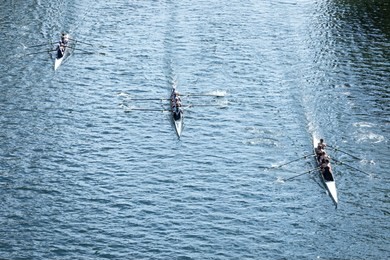 overhead view of three four-person crew teams racing rowing shells on a calm lake