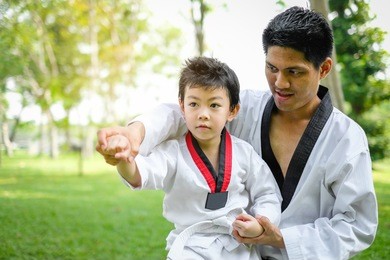 father is teacher teaching taekwondo kids, children boy are learning taekwondo in the nature park