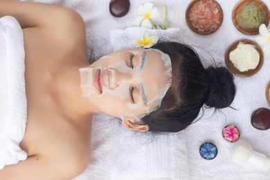 asian woman lying with a sheet mask on her face.wellness body care and spa aromatherapy concept.