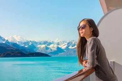 luxury travel alaska cruise holiday woman relaxing on balcony looking at view of mountains and nature landscape. asian girl sunglasses tourist.