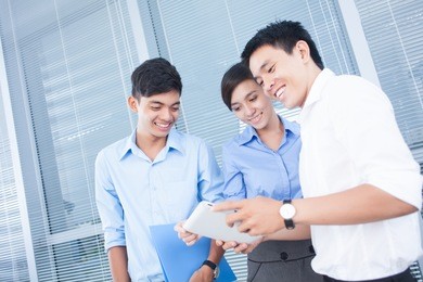 group of office workers looking at digital tablet and smiling