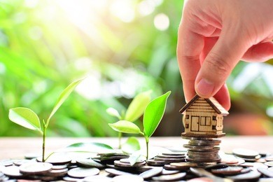hand putting house model on coins saving for concept investment fund mortgage finance and home loan 