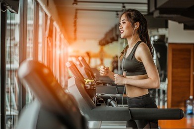 portrait of fitness woman running on treadmill in gym listening to music.exercising concept.fitness and healthy lifestyle.