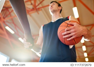 anonymous basketball players standing on court before match and greeting each other with handshake. 