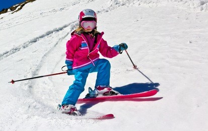 girl on skis in soft snow on a sunny day in the mountains, on a steep slope.