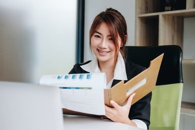 asia business accounting concept, woman using  smart phone and laptop computer to working finance and budget in office.