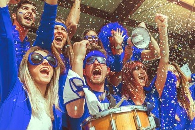 group of fans dressed in blue color watching a sports event in the stands of a stadium