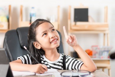 asian little girl doing homework and pointing finger on wooden table select focus shallow depth of field