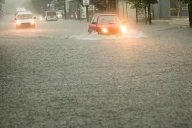 street of the city flooded after heavy rains. cars driving on the flood