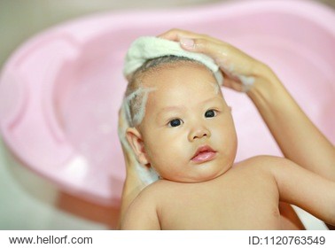 adorable six month year old infant baby boy having a bath and shampooed by mother.