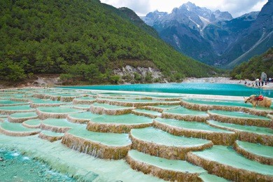 white water river waterfall at the cliffs and brooks at the foot of jade dragon snow mountain, lijiang, yunnan china.