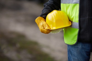 builder with yellow helmet and working gloves on building site