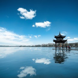 ancient pavilion against a blue sky and reflection in the west lake at hangzhou,china.