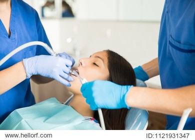 midsection of medical team examining teenage girl with dental equipment at clinic