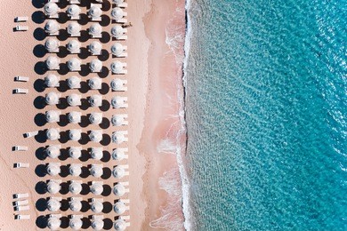aerial view of amazing turquoise sea with white umbrellas and sun loungers. beautiful sunny summer day in sardinia, mediterranean sea, italy. 