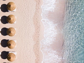 aerial view of amazing turquoise sea with brown straw umbrellas and sun loungers. beautiful sunny summer day in sardinia, mediterranean sea, italy. 