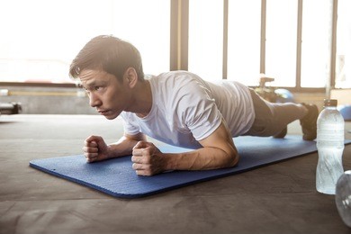 asian man exercising in the gym, he doing a "plank"