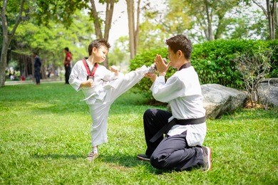 father is teacher teaching taekwondo kids, children boy are learning taekwondo in the nature park