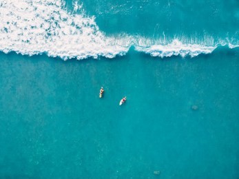 aerial view of surfers and wave in tropical ocean. top view