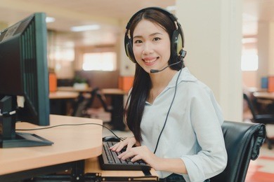 beautiful asian young woman customer service executive working at office by the table in headphones. call center