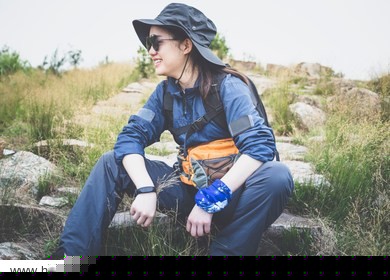 a beautiful asian woman in outdoor mountaineering dress is resting on the stone steps.