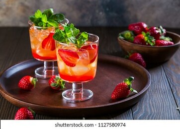 strawberry lemonade, refreshing summer mojito with strawberries, lime and mint on wooden background. copy space