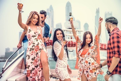 group of friends making party on a yacht in dubai - happy people having a fancy party on a luxury boat