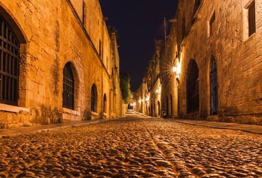 night photo of ancient street of the knights in rhodes city on rhodes island, dodecanese, greece. stone walls and bright night lights. famous tourist destination in south europe
