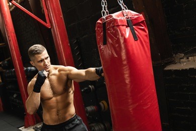 strong young mma fighter and red punching bag in the gym