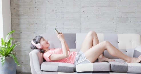 woman lying on sofa and listen music happily