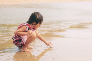 girl of asian are drawing on beach with sunlight.