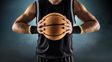 basketball ball in a male hands, player in black with orange sport ball.