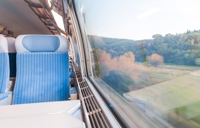 inside cabin of modern express train. nobody in blue chairs at window. motion blur. comfortable chairs and table in foreground, nature outside window. travel, france, europe.