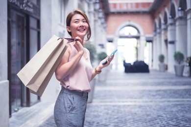 beautiful asian thai girl in shopping.happy woman with shopping, girls holding shopping bags using a smart phone and smiling while standing outdoors enjoying in shopping.consumerism,lifestyle concept.