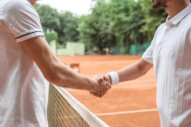 cropped view of tennis players shaking hands after game on court